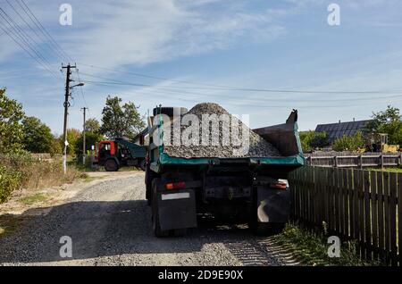 Big dump truck on suburban street, rear view. Waiting for dumping gravel for building and reconstruction roadway. Stock Photo