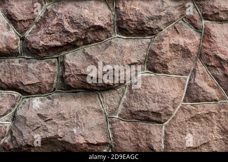 The surface of the masonry is made of roughly hewn large red stones, fitted together. Stock Photo