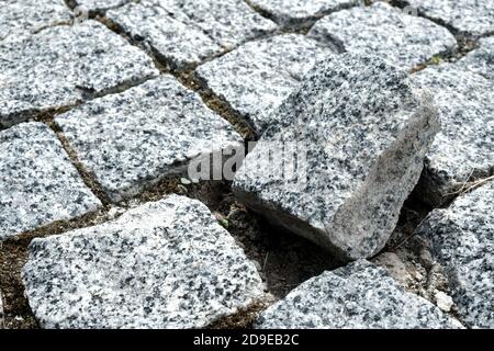 Unique broken stone of the cobblestone street in an old medieval city. Outsider of a community. Damaged, alone and different. Paved boulevard Stock Photo