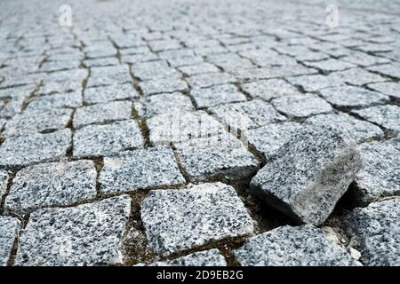 Single cobble out of the structure on a cobblestone street in an old medieval city. Gray paved boulevard made of stones. Urban footpath mosaic Stock Photo