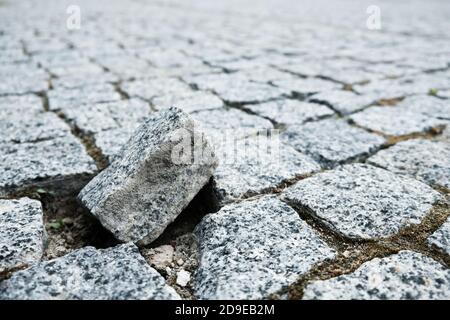 Broken piece of cobblestone street in an old medieval city. Paved boulevard made of stones. Urban footpath mosaic from rock material. Being unique Stock Photo