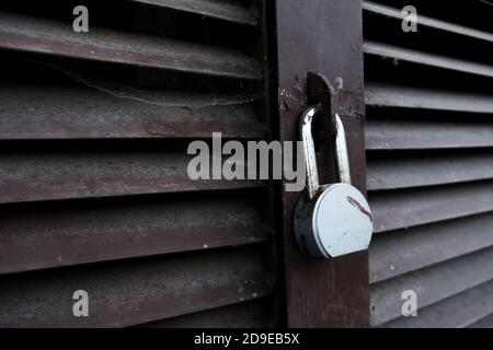 Abandoned locked door of a garage, shed or warehouse. Old and forgotten metal aged padlock on a closed secure facility. Spider web all over. Prison Stock Photo