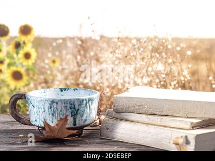 Autumn composition with books and a beautiful Cup on the background of a field and sunflowers. Stock Photo