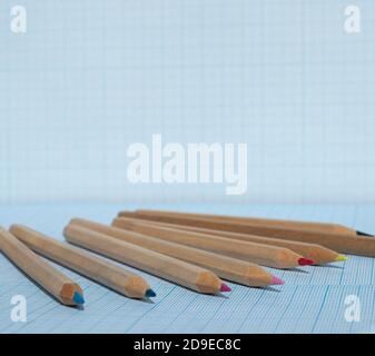 Wooden pencils with colored leads on blue squared paper. Copy space for text. Stock Photo