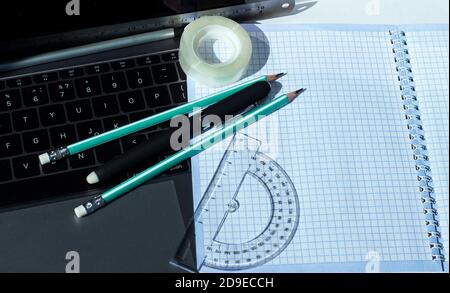 Stationery and squared notebook on laptop keyboard. Copy space for text. Template for corporate student and school design. Stock Photo
