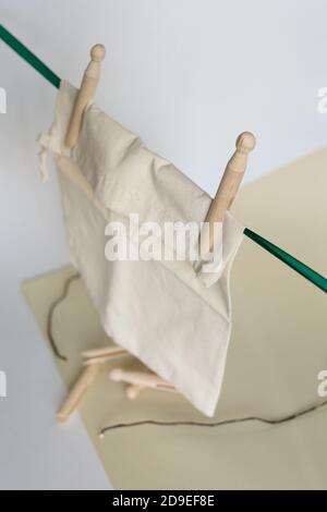 White tissue pouch hanging on wooden clothespins in light background. Stock Photo