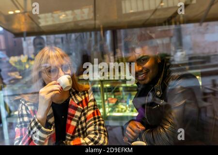 young multiethnic couple is having breakfast sitting in a cafe during the Christmas season Stock Photo