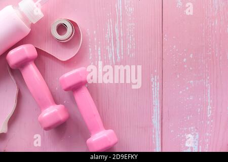 pink color dumbbell, measurement tape and water bottle on table  Stock Photo