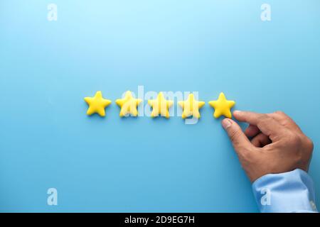 Customer review concept. Rating golden stars on blue background  Stock Photo