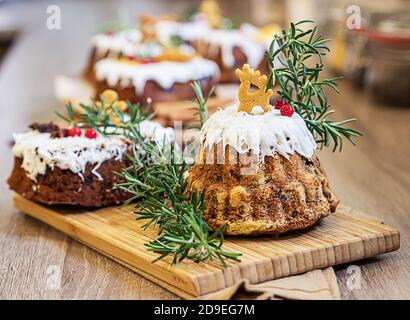 Christmas fruit cake, pudding decorated with gingerbread cookies, rosemary and lingonberry on wooden board. Homemade traditional Christmas dessert. Stock Photo