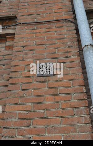 Ventilation grill on a brick wall. Gutter gray pipe. Stock Photo