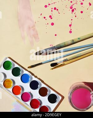 Supplies for painting on a light background with purple splashes. Paints. Brushes. Free space for text. Stock Photo