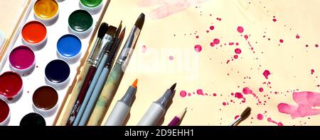 Supplies for drawing. Watercolor paints brushes pencils watercolor markers on a light background with purple blots. Copy space. Banner.  Stock Photo