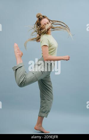 Playful young woman with stylish blond afro braids over blue background Stock Photo