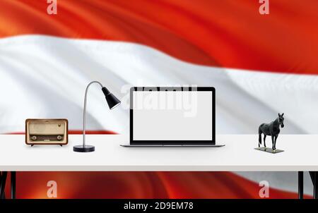 Austria national flag background with workspace, desktop computer and office accessories on white modern table. Stock Photo