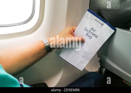 Passenger holding air sickness vomit bag in airplane Stock Photo