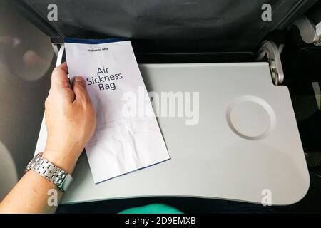 Passenger holding air sickness vomit bag in airplane Stock Photo