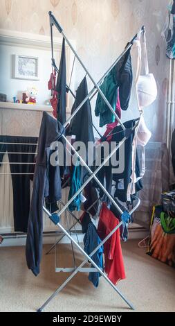 Drying recently washed clothes indoors on a drying rack. Stock Photo