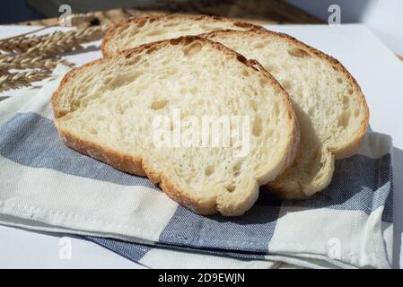 Three pieces of wheat bread on a kitchen towel. Wheat ears are near. Stock Photo