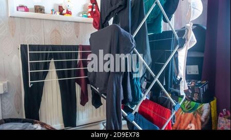 Drying recently washed clothes indoors on a drying rack. Stock Photo