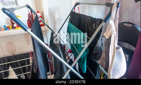 Drying recently washed clothes indoors on a drying rack. Stock Photo