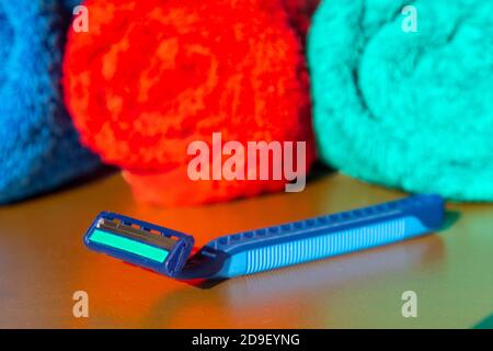 The razor lies on a mirrored bath table against the background of three towels. Stock Photo