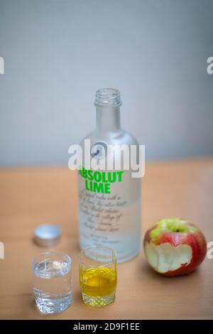 A bottle Absolut Vodka, one small glass Absolut Vodka and oil and apple on the wooden table. Warsaw, Poland. 05.11.2020 Stock Photo