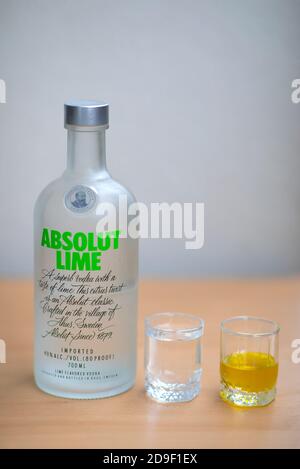 A bottle Absolut Vodka, one small glass Absolut Vodka and oil on the wooden table. Warsaw, Poland. 05.11.2020 Stock Photo