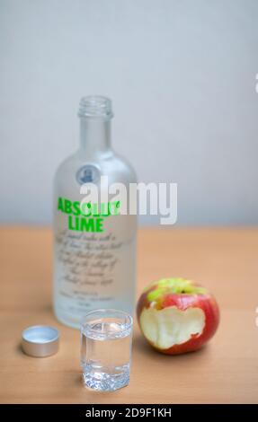 A bottle, one small glass Absolut Vodka and apple on the wooden table.Warsaw, Poland. 05.11.2020 Stock Photo