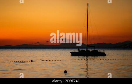 Small rental yacht drifts in the Adriatic Sea at sunset.Beautiful evening on seaside.Relax and enjoy calm water on ocean beach.Travel destination for Stock Photo