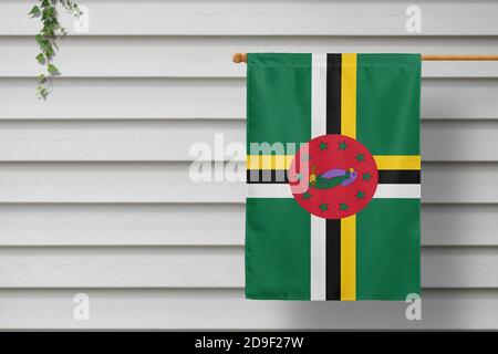 Dominica national small flag hangs from a picket fence along the wooden wall in a rural town. Independence day concept. Stock Photo