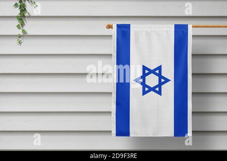 Israel national small flag hangs from a picket fence along the wooden wall in a rural town. Independence day concept. Stock Photo