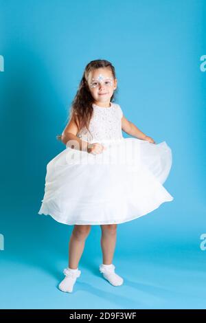 full-length portrait of a girl in a white Princess dress with a swirling skirt and dancing isolated on a blue background Stock Photo