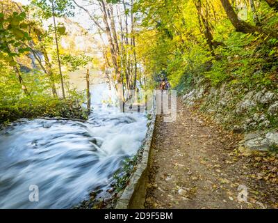 People visitors humans walking walkders going away along flowing river in National park Plitvice lakes, Croatia Stock Photo