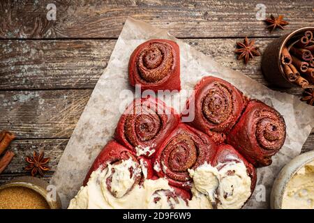Homemade cinnamon rolls red velvet with cream cheese glaze on wooden background, top view Stock Photo