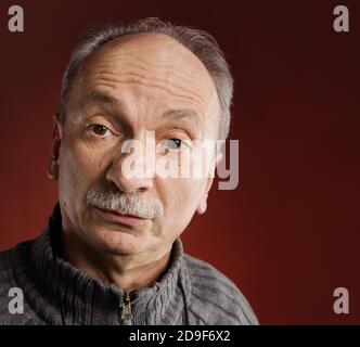 Feeling confused. Portrait of a surprised elderly man on red background Stock Photo