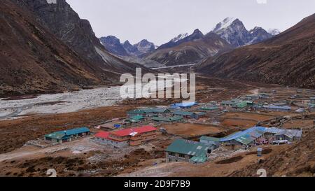 Aerial panorama view of small Sherpa village Pheriche (altitude 3,840 m) located in a valley with riverbed and snow-covered mountain range in Nepal. Stock Photo