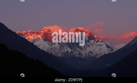 Stunning panorama view of mighty Mount Everest massif illuminated by the red colored evening light at sunset viewed from Sherpa village Namche Bazar. Stock Photo