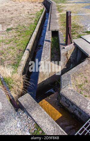 Small concrete irrigation canal in the countryside Kyoto Prefecture, Japan. Select Focus. Stock Photo