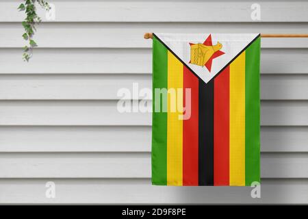 Zimbabwe national small flag hangs from a picket fence along the wooden wall in a rural town. Independence day concept. Stock Photo