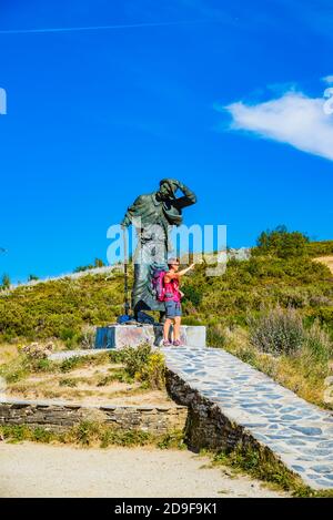 A pilgrim next to the monument to the pilgrim of the Alto de San Roque (altitude of 1270 m), work of the Galician sculptor José María Acuña, is a stat Stock Photo