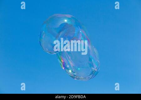 Surreal bubbles floating a clear blue sky on a sunny day and glittering in the sun shine. Created by a Bubbleologist at an outdoor event. UK (120) Stock Photo