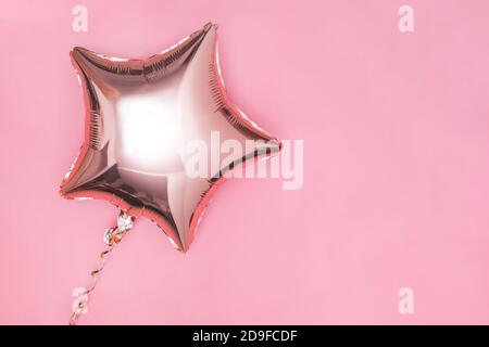 Gold glitter foil star shaped balloon isolated on pink Stock Photo