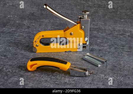 Stapler for furniture, staples, staple remover on a gray background Stock Photo