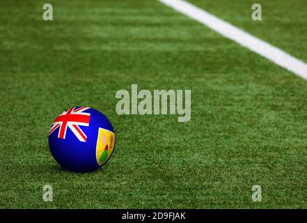 Turks And Caicos Islands flag on ball at soccer field background. National football theme on green grass. Sports competition concept. Stock Photo