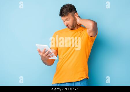 confused man in t-shirt using digital tablet on blue Stock Photo