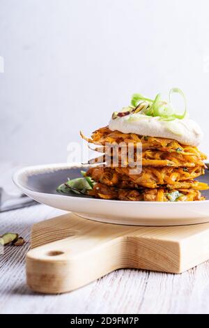 Sweet potato fritters with hummus and pistachios on rural wooden table, vegan meal Stock Photo