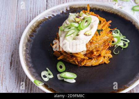 Sweet potato fritters with hummus and pistachios on rural wooden table, vegan meal Stock Photo