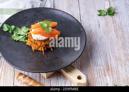 Sweet potato fritters with hummus, smoked salmon and pistachios on rural wooden table Stock Photo