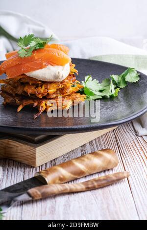 Sweet potato fritters with hummus, smoked salmon and pistachios on rural wooden table Stock Photo